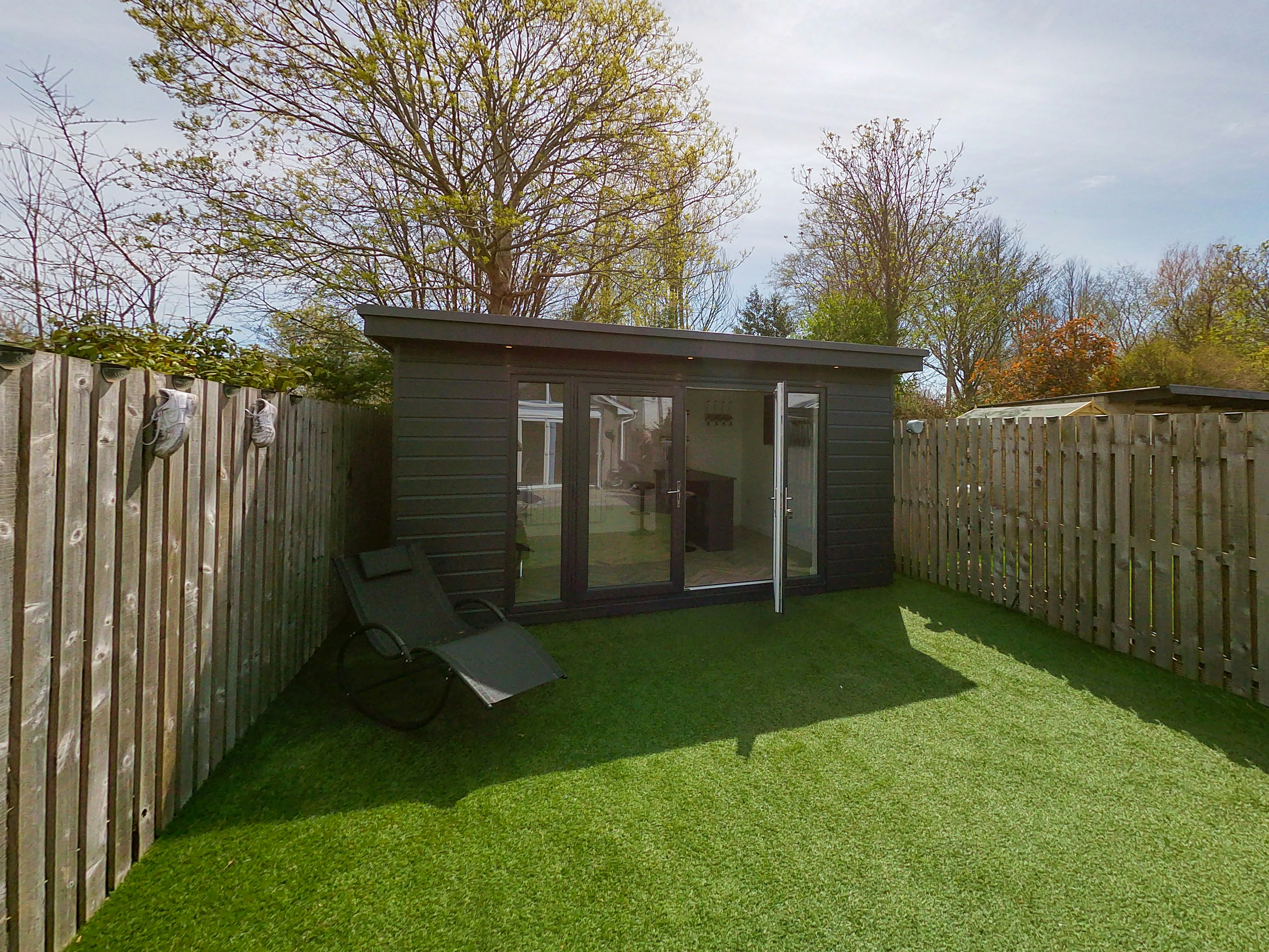 Small garden outbuilding in a grassed backyard